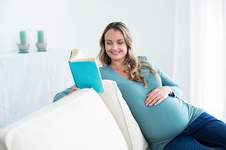 Pregnant woman reading a book on the couch.jpeg